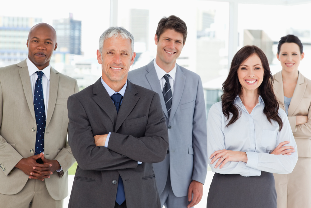 Smiling and confident business team standing in front of a bright window Smiling and confident business team standing in front of a bright window